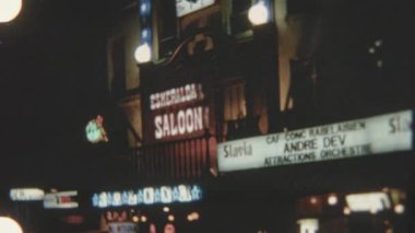 At nalı logosuna sahip bir Esmeralda Salonu tabelası Paris 'te geceleri belirgin bir şekilde sergileniyor, 8 mm' lik filmle çekiliyor ve parlak ışıklarla aydınlatılıyor, canlı, nostaljik bir atmosfer yaratıyor..