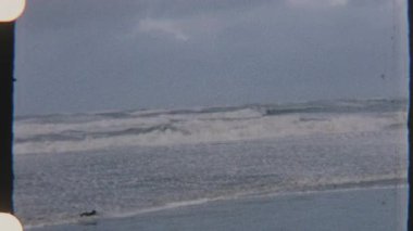 Okyanus dalgaları kıyıya çarpıyor, 8mm 'lik filme çekiliyor, güçlü ve dinamik bir görsel ortam yaratıyor..