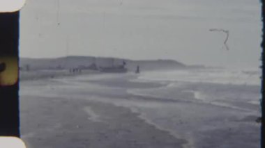 Tekneler kumlu bir sahilde dinleniyor, 8mm 'lik bir filme çekiliyor, okyanus dalgaları kıyıya vururken, yumuşak doğal ışık altında manzaralı bir kıyı manzarası çerçeveleniyor..