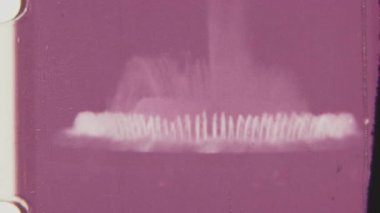 Bu zarif çeşme, 8mm 'lik klasik bir filmde, yumuşak pembe tonlarda uzun dikey akımlar içerir, film tahılları nostaljik, sinematik bir dokunuş ekler..