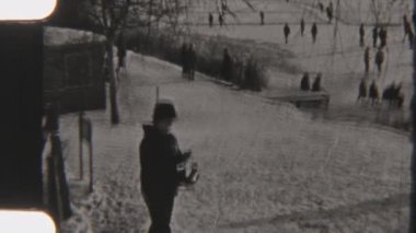 Diğerleri arka planda kayarken, 8 mm 'lik Retro film kaykay kayan ve bağlarını çözen birini yakalıyor. Yumuşak film taneleri ve serin kış tonları nostaljik bir hissi çağrıştırıyor.