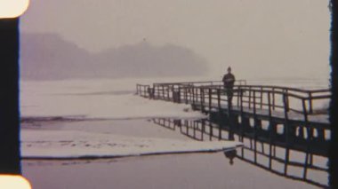 Retro 8 mm 'lik film bir adamı ayakta yakalar ve kışın iskelede yürür. Yumuşak tanecikler ve sessiz tonlar nostaljik, sakin ve sakin bir kış atmosferini çağrıştırıyor..