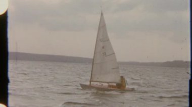 Güçlü rüzgar ve dalgalar içinde dalgalı suya karşı sallanan bir adam küçük bir tekne kullanıyor. Klasik 8mm film görüntüsü nostaljik bir his katıyor..