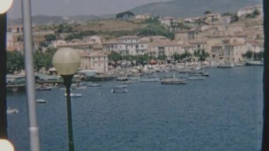 Porto Azzurro 'nun 8mm' lik Retro filmi. Limana yanaşmış tekneleri olan sakin bir sahil köyü. Sahne, köyün bir yamaçtaki manzarasını gözler önüne seriyor.