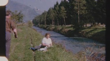 Bir kadın nehir kenarında oturur ve bir erkek pikniğe katılmak için yanına yaklaşır. Arkasında nehir ve dağlar olan ağaçlar nostaljik 8 mm 'lik bir filme çekilir..