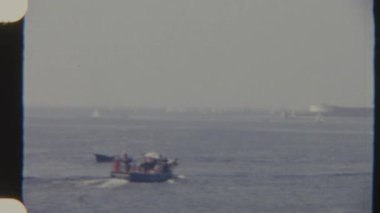 İçinde insanların olduğu küçük bir tekne sakin bir denizi aşar, 8 mm 'lik bir filme çekilir, huzurlu ve huzurlu bir görsel ortam yaratır..