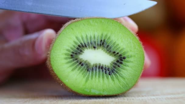 Hand slicing a kiwi with a knife — Stock Video