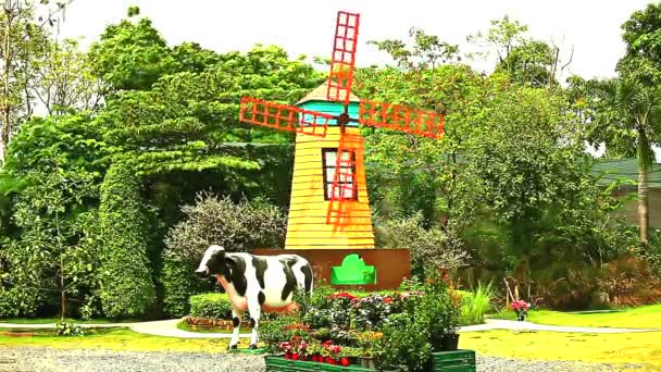 Moulin à vent avec vache dans un parc vert — Video