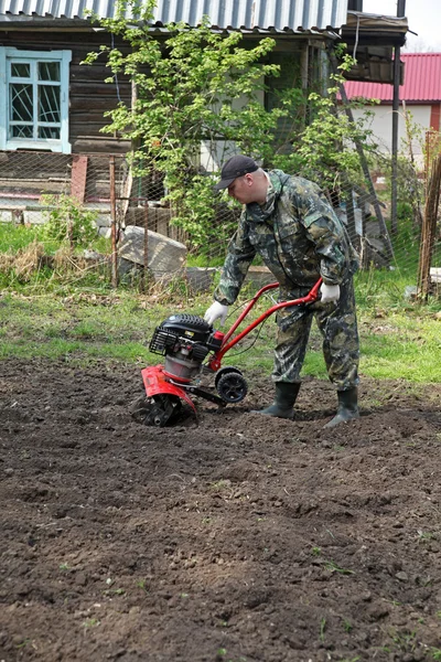 Homem trabalhando no jardim preparando cultivador de terra — Fotografia de Stock