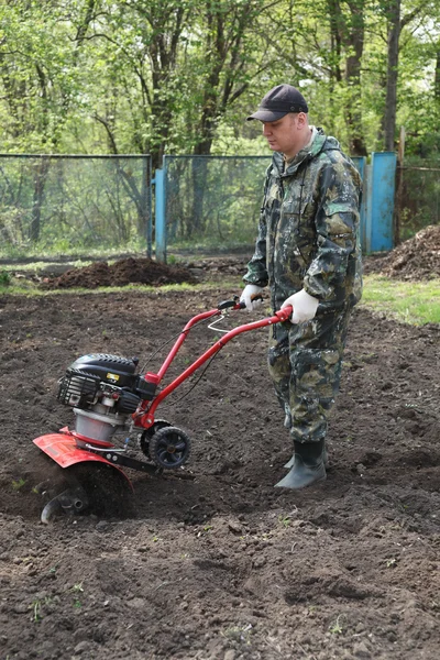 Homem trabalhando no jardim preparando cultivador de terra — Fotografia de Stock