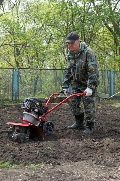 Homem trabalhando no jardim preparando cultivador de terra — Fotografia de Stock