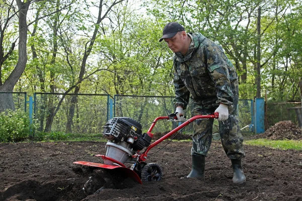 Hombre trabajando en el jardín preparando cultivador de tierra —  Fotos de Stock