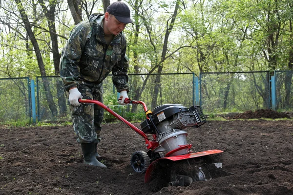 Człowiek pracuje w ogrodzie przygotowanie ziemi kultywator — Zdjęcie stockowe