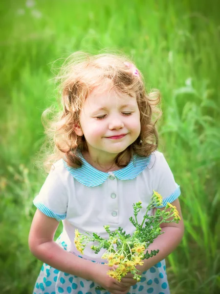 Little curly girl with closed eyes and a bouquet of wildflowers, — Stock Photo, Image
