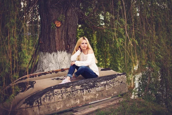 Young women with blond long hair seating on the old boat — Stock Photo, Image