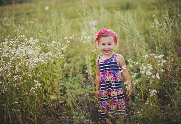 Petite fille souriante en robe colorée sur le champ d'été — Photo