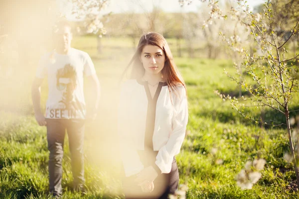 Joven hermosa pareja en flores de primavera — Foto de Stock