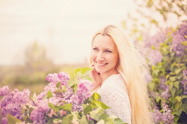 Joven mujer sonriente con flores violetas — Foto de Stock