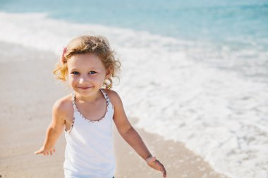 Sevimli gülümseyen mutlu küçük plaj vaca kıvırcık saçlı kız