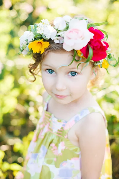 Kleines Mädchen im Blumenkranz im Garten — Stockfoto