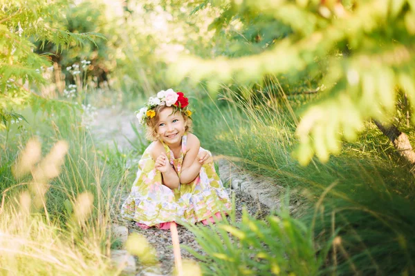 Bambina in corona di fiori in giardino — Foto Stock