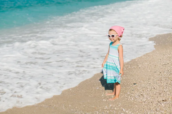 Чарівна щаслива усміхнена маленька дівчинка з кучерявим волоссям на пляжі — стокове фото