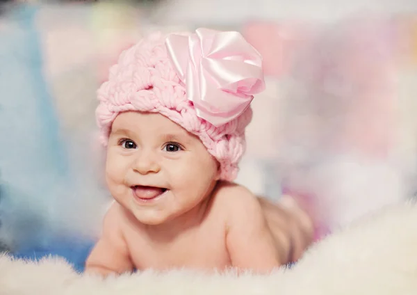 Sorrindo bebê menina em um chapéu de malha rosa deitado sobre o cobertor — Fotografia de Stock