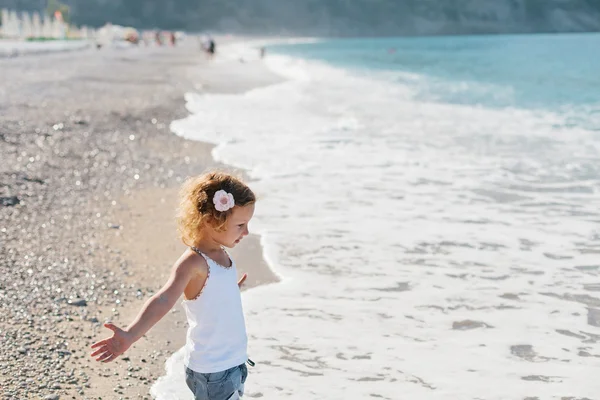 Schattig gelukkig lachend meisje met krullend haar op strand vaca — Stockfoto