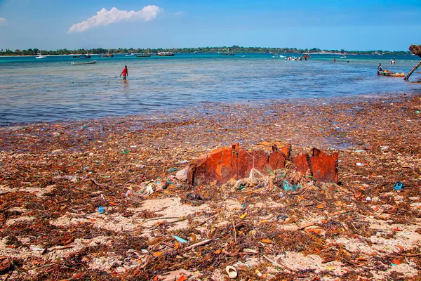 Île Wasini, Kenya, AFRIQUE - 26 février 2020 : Un homme se tient dans les ordures en mer. Ce sont des plastiques dans l'océan Indien. Le bordel gâche la vue sur le magnifique océan Indien. — Photo