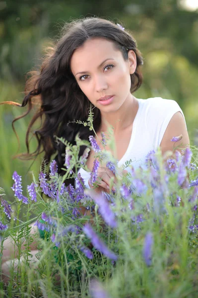 Portret van een mooi meisje met bloemen in de zomer — Stockfoto