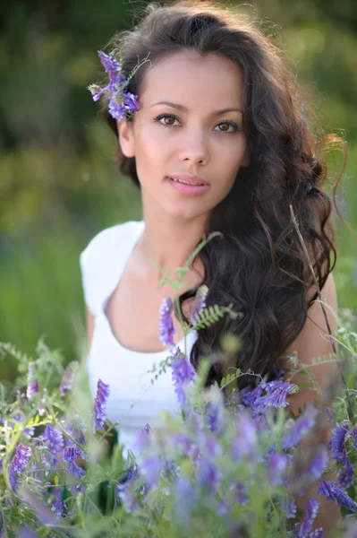 Porträtt av en vacker flicka med blommor på sommaren — Stockfoto