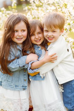 Baharda doğada üç çocuğun portresi.