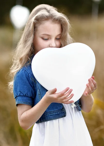 Πορτρέτο του ένα μικρό κορίτσι σε ένα πεδίο με λευκά μπαλόνια — Φωτογραφία Αρχείου