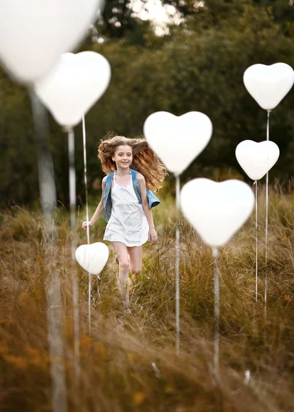 Πορτρέτο του ένα μικρό κορίτσι σε ένα πεδίο με λευκά μπαλόνια — Φωτογραφία Αρχείου