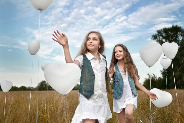 Portrait of a little girls in a field with white balloons — Stock Photo, Image