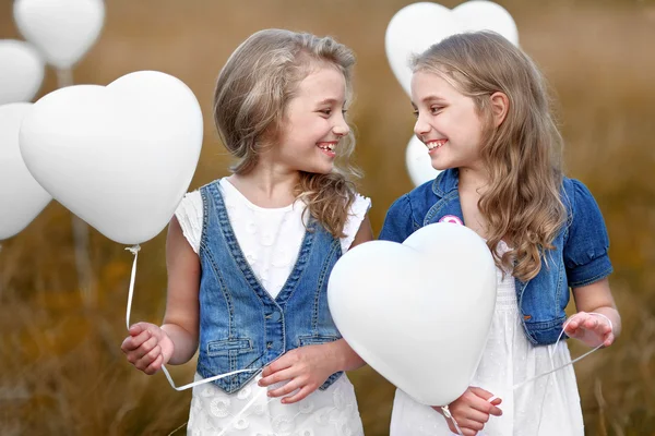 Portrait of a little girls in a field with white balloons — Stock Photo, Image