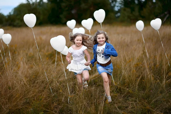 Egy kislány, a mező fehér léggömbökkel portréja — Stock Fotó