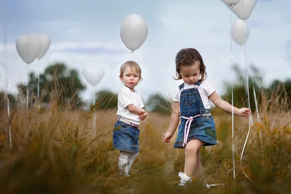 Retrato de una niña en un campo con globos blancos —  Fotos de Stock