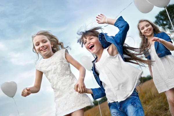 Porträtt av en små flickor i ett fält med vita ballonger — Stockfoto