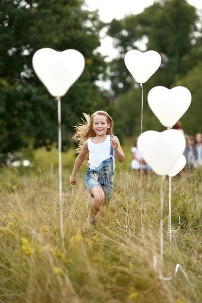 Portret van een kleine meisjes in een veld met witte ballonnen — Stockfoto