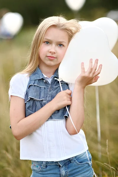 Porträtt av en liten flicka i ett fält med vita ballonger — Stockfoto