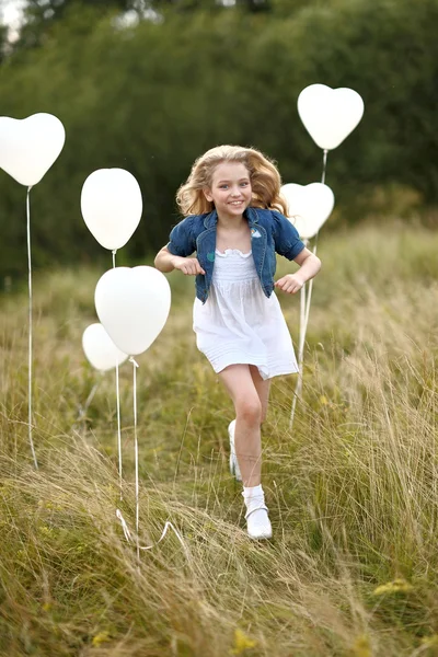 Portrait of a little girl in a field with white balloons — Stock Photo, Image