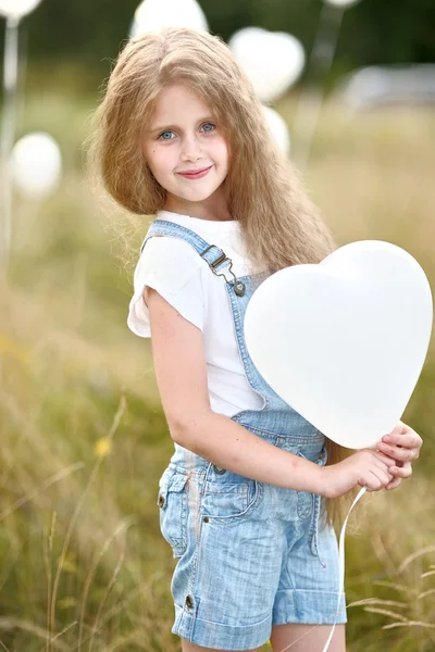 Portrait of a little girl in a field with white balloons — Stock Photo, Image