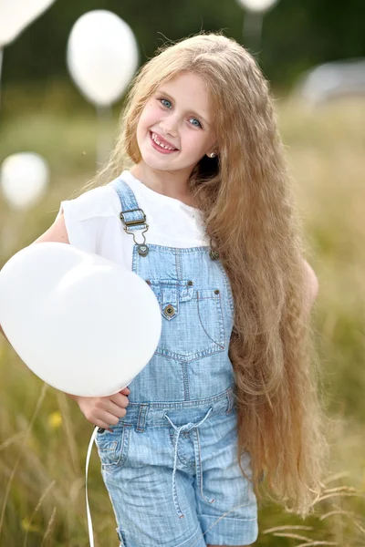 Portrait of a little girl in a field with white balloons — Stock Photo, Image