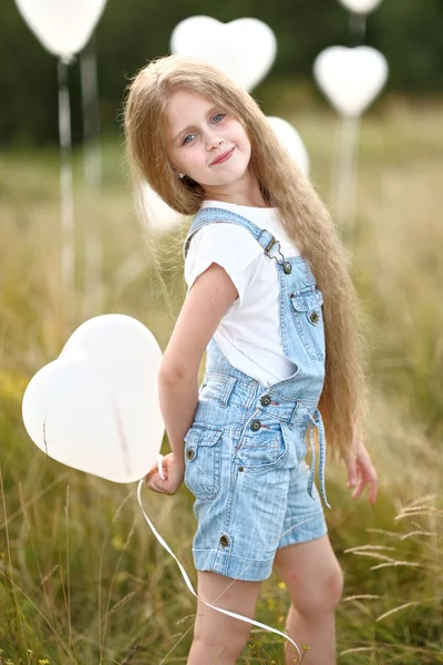 Retrato de una niña en un campo con globos blancos — Foto de Stock