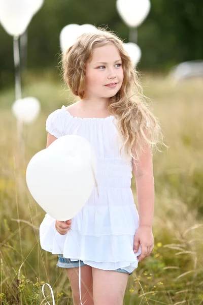 Retrato de uma menina em um campo com balões brancos — Fotografia de Stock