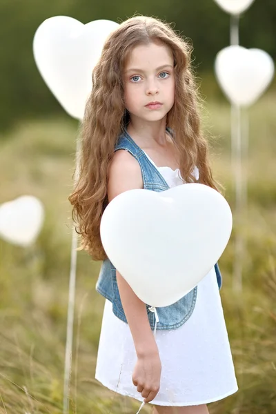 Portret van een klein meisje in een veld met witte ballonnen — Stockfoto