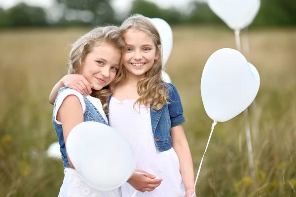 Porträtt av en små flickor i ett fält med vita ballonger — Stockfoto