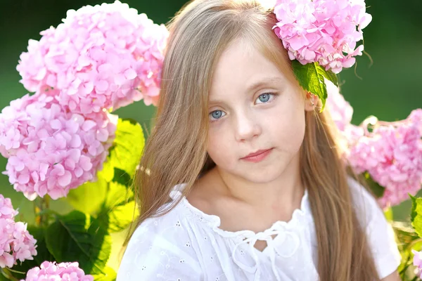 Портрет маленької дівчинки з квітами гортензія — стокове фото