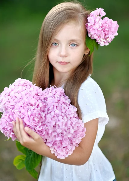 Porträtt av liten flicka med blommor hortensia — Stockfoto